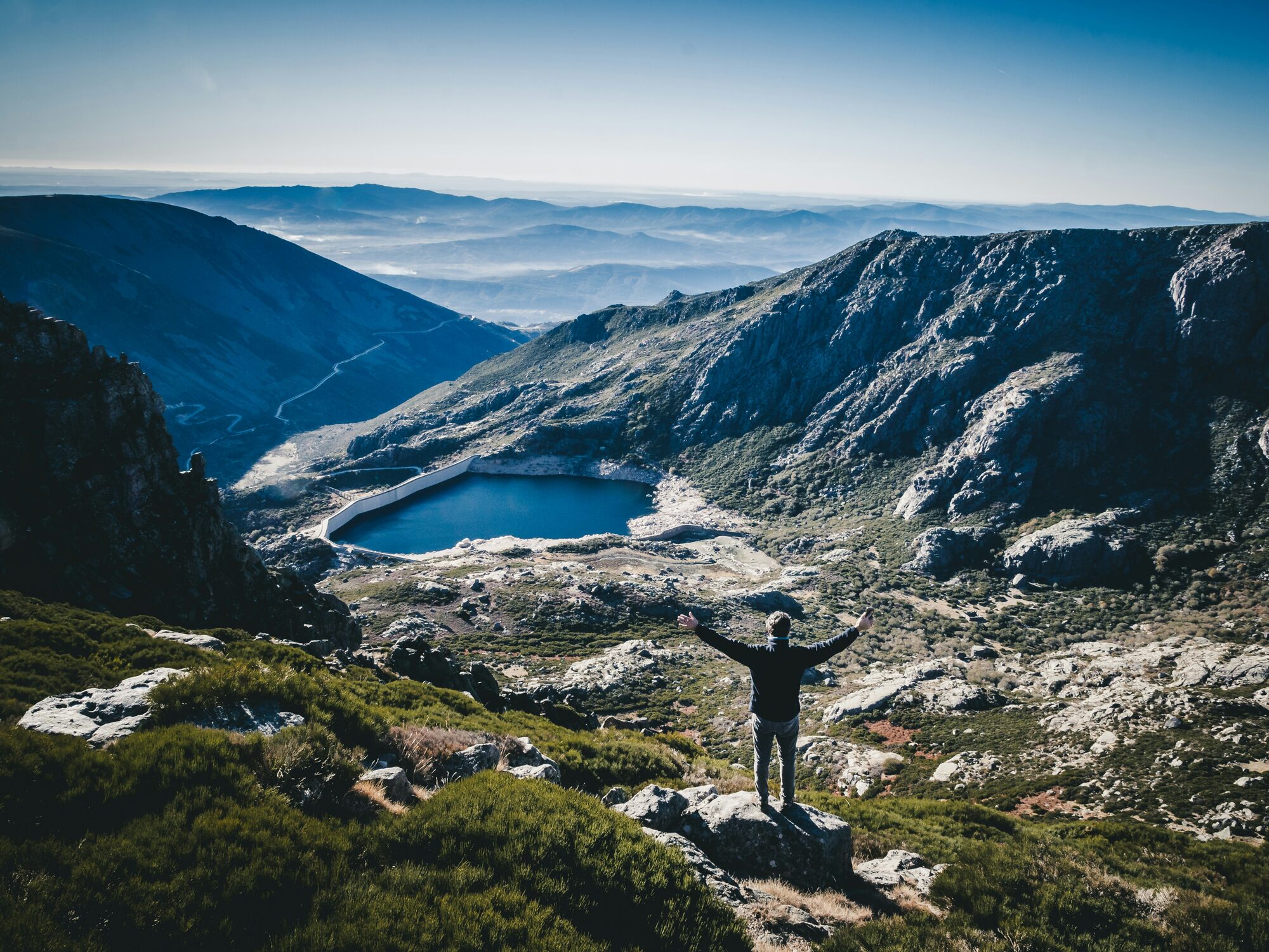 A hiker standing above a glacial lagoon in the Serra da Estrela mountains, Beira Interior, Portugal